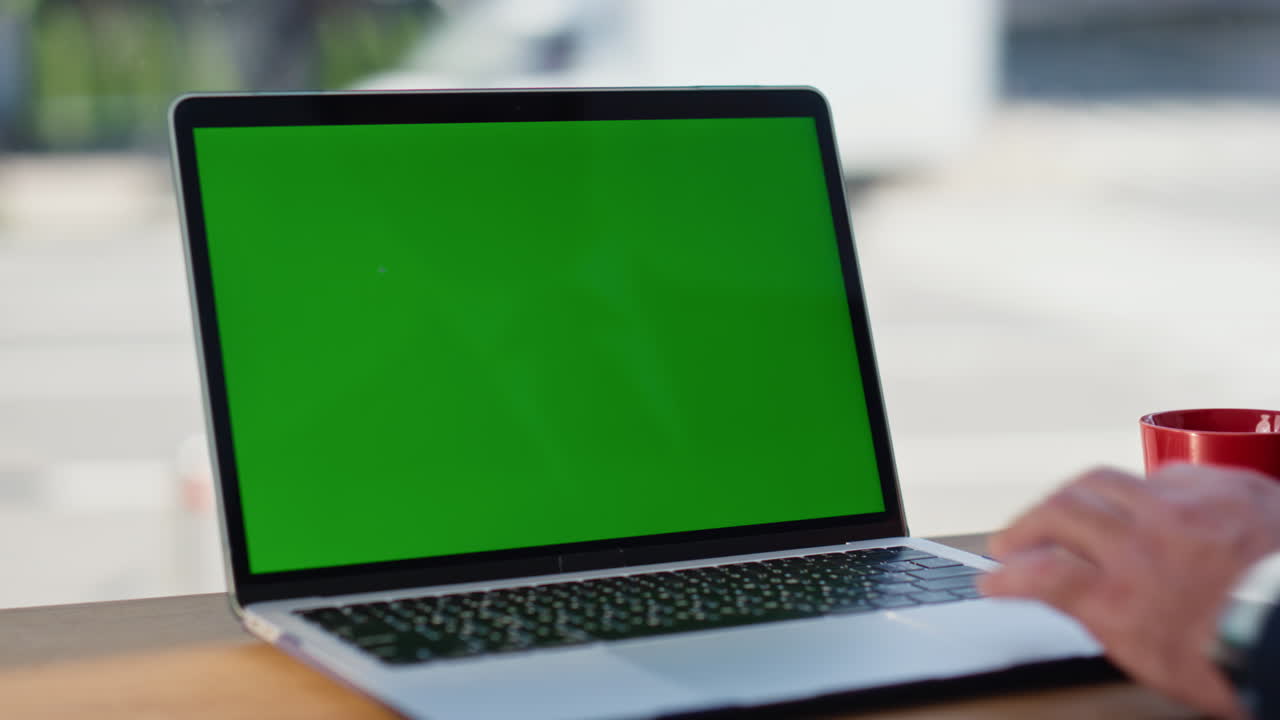 Primo piano di un uomo che digita su un portatile con greenscreen seduto nella hall di un hotel. Manager al lavoro