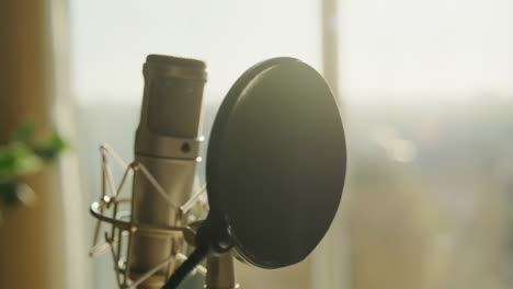 close-up of a studio microphone with pop filter in warm light