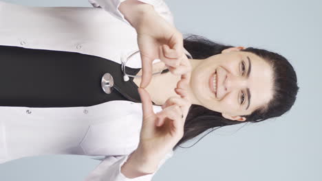 video vertical del médico haciendo corazón mirando a la cámara.