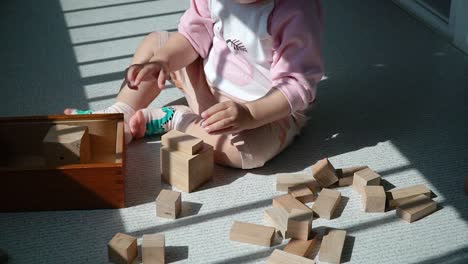 niño pequeño apilando bloques de juguete de madera en el balcón - educación multiétnica asiática coreana-ucraniana de niñas