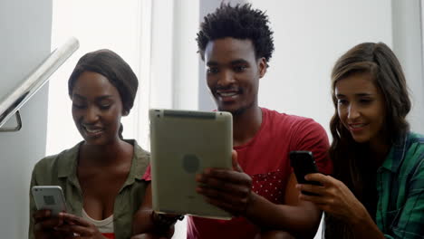 Freunde-Interagieren-Auf-Der-Treppe-Mit-Mobiltelefon-Und-Digitalem-Tablet