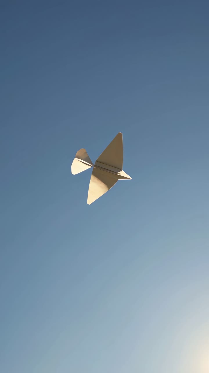 A minimalist video concept showing a paper airplane soaring against a clear blue sky