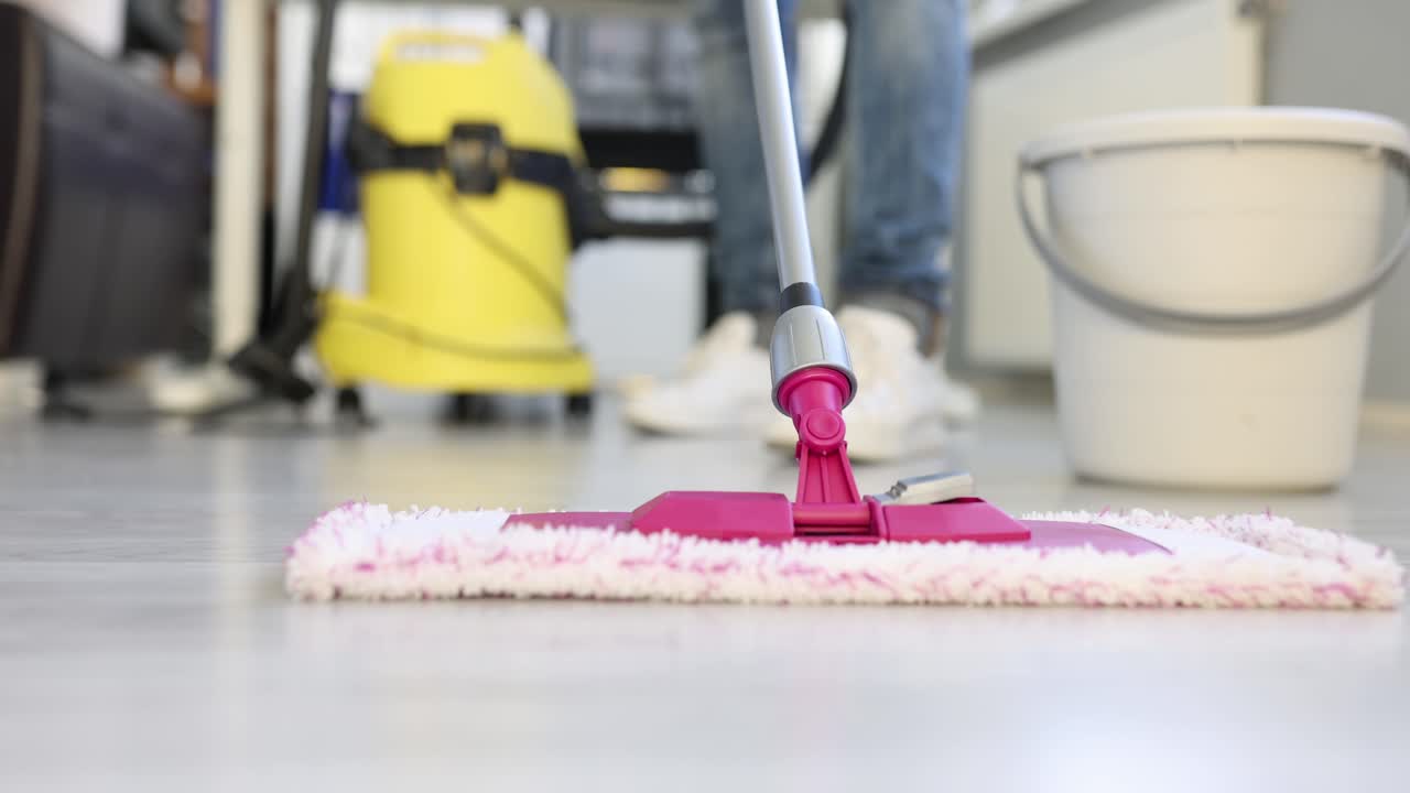 Woman uses flat wet mop cleaning floor in house