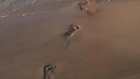 girl walking on a sandy beach leaving footprints behind her