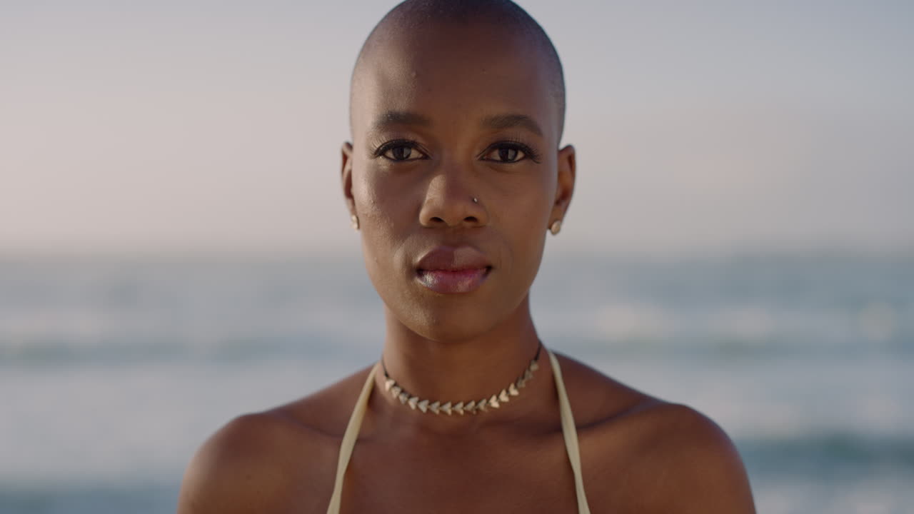 portrait of attractive young african american woman looking calm pensive enjoying warm sunny seaside beach slow motion