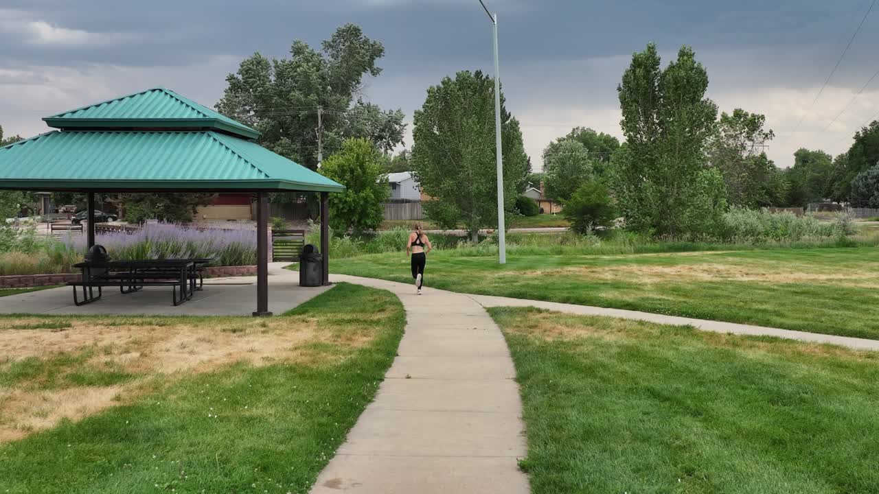 Fitness expert running quickly down a park path in slow motion. Drone 4k shot
