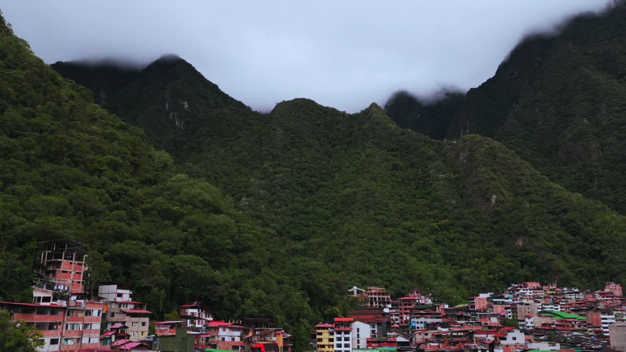 Aguas Calientes Machu Picchu town rainy season cloudy afternoon Peru aerial drone Peruvian Andes Mountains Urabumba river jungle lower highlands Inca trail citadel landscape buildings circle right
