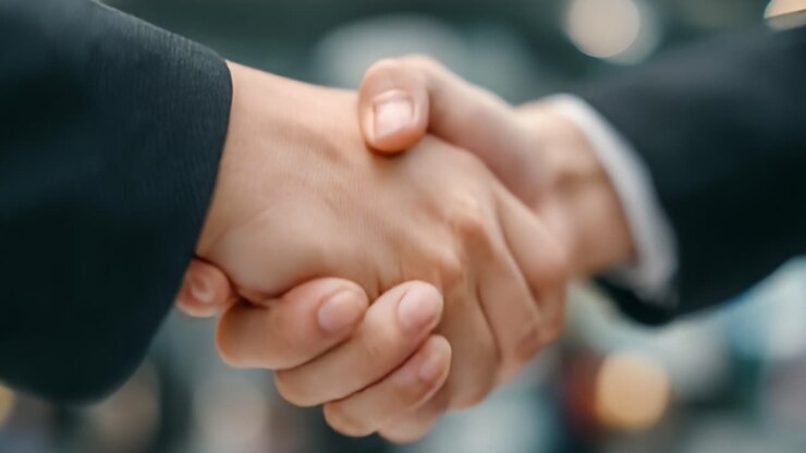 Una stretta di mano dinamica che cattura l'essenza di accordi e partnership in contesti professionali, simboleggiando fiducia e collaborazione tra individui