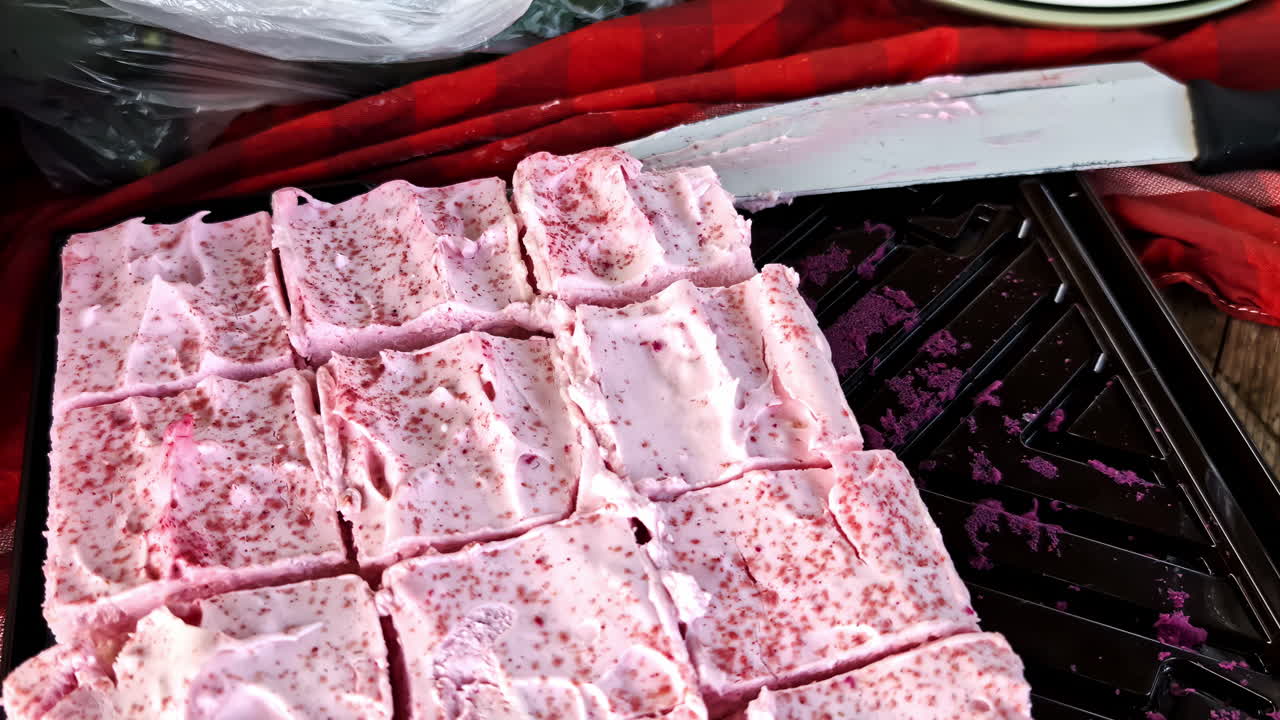 Closeup of Sliced pink sponge cake on red tablecloth with knife