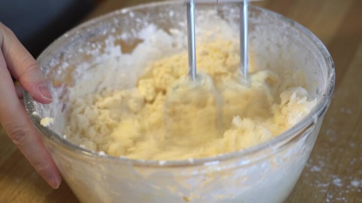 mixing butter and flour in a mixing bowl using an electric mixer