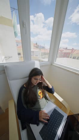 teenage girl working on laptop at home
