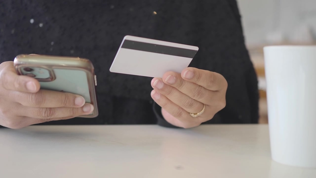 Persona che tiene carta di credito e smartphone per acquisti online