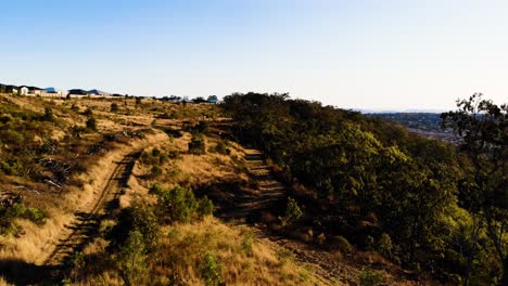 Un-Dron-Sigue-Un-Camino-De-Tierra-Sobre-Una-Hermosa-Pradera