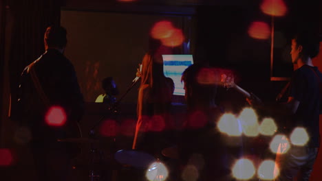 music bandmates performing on moody stage, mixing guitars drums with animated waveform and bokeh