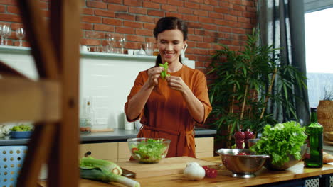 smiling girl cooking healthy salad at home. woman tearing lettuce leaves on bowl