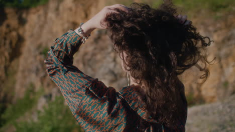 Una-Mujer-Con-Camisa-Alborota-Su-Cabello-Rizado-Y-Observa-Una-Antigua-Cantera