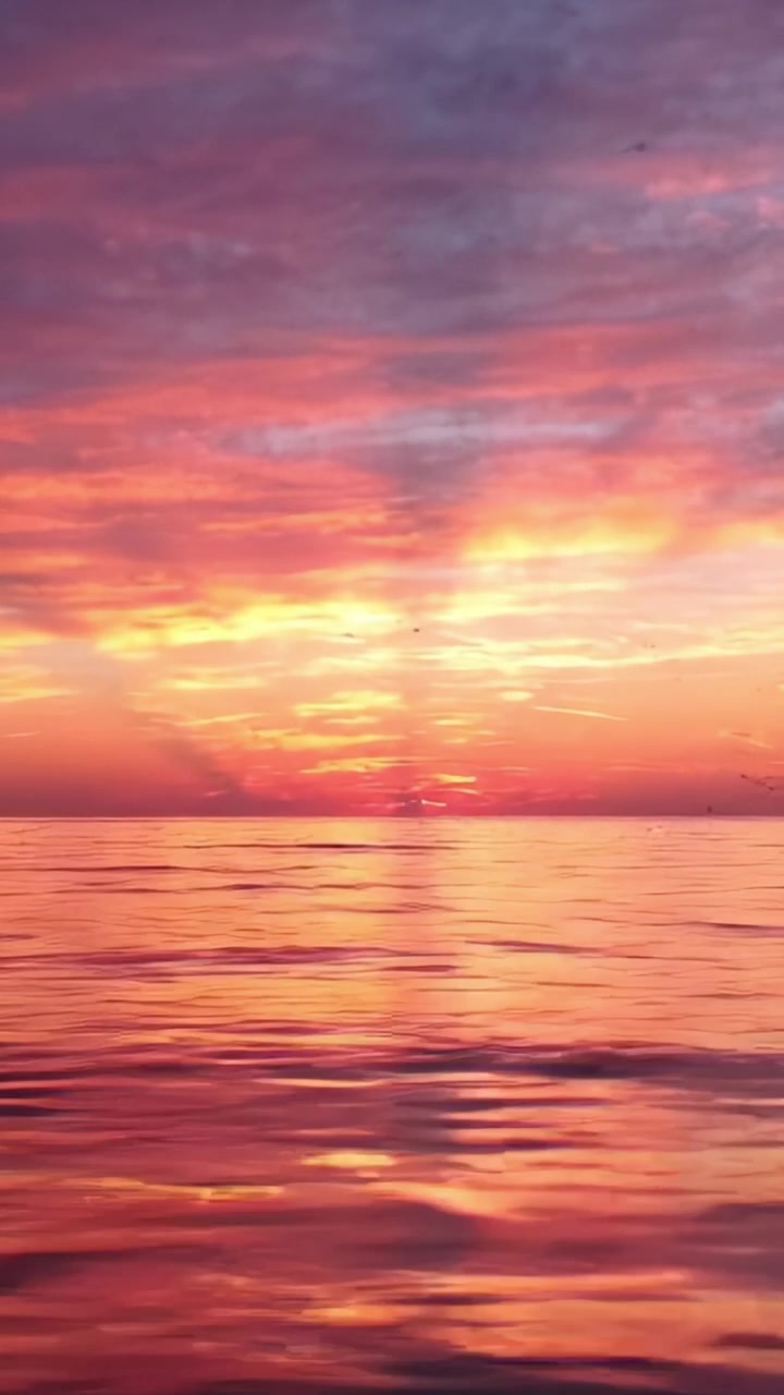 Spektakulær solnedgang over rolige vande: Et fantastisk farvespil, der reflekteres på den rolige havoverflade