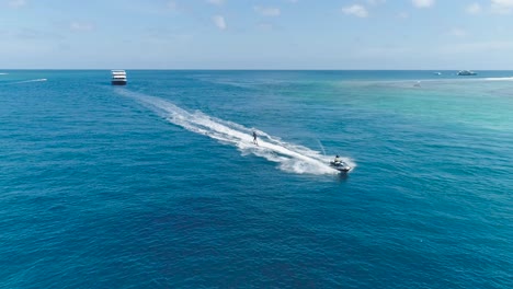 drone tracking shot over man riding a jet ski at tropical paradise exotic island with blue and turquoise ocean sea view. adventure concept for tourist attraction at beach vacation sport at summer day