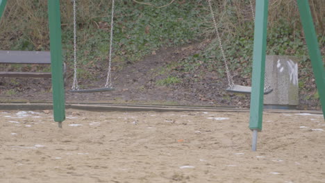 empty swings swinging near the sandy shore during daytime