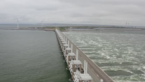 toma aérea volando hacia atrás sobre la barrera de marejada ciclónica del este de scheldt en zelanda, los países bajos, en un día tormentoso