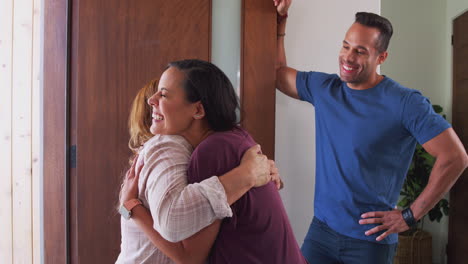 Couple-Greeting-Senior-Mother-At-Front-Door-As-She-Comes-To-Visit