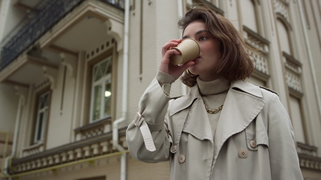 Young woman drinking coffee to go on street. Girl enjoying hot latte outdoor.