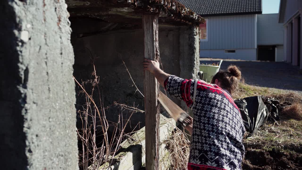 мужчина использует пилу, чтобы разрезать старый опорный столб, расположенный на ферме в индере фосен, округ тронделаг, норвегия - статический кадр