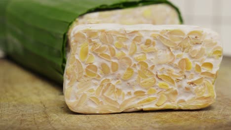 Frische-Charge-Tempeh,-Traditionelles-Indonesisches-Gericht-Aus-Fermentierten-Sojabohnen,-Eingewickelt-In-Bananenblätter-Auf-Einem-Holzschneidebrett