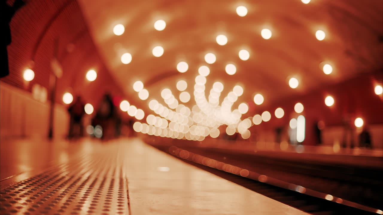 Blurry view of people and trains moving through the Monaco train station with bright lights in Monte Carlo, Monaco