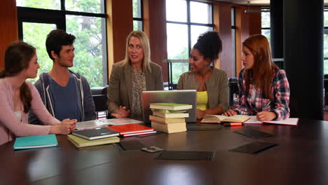 estudiantes y tutor discutiendo en la biblioteca