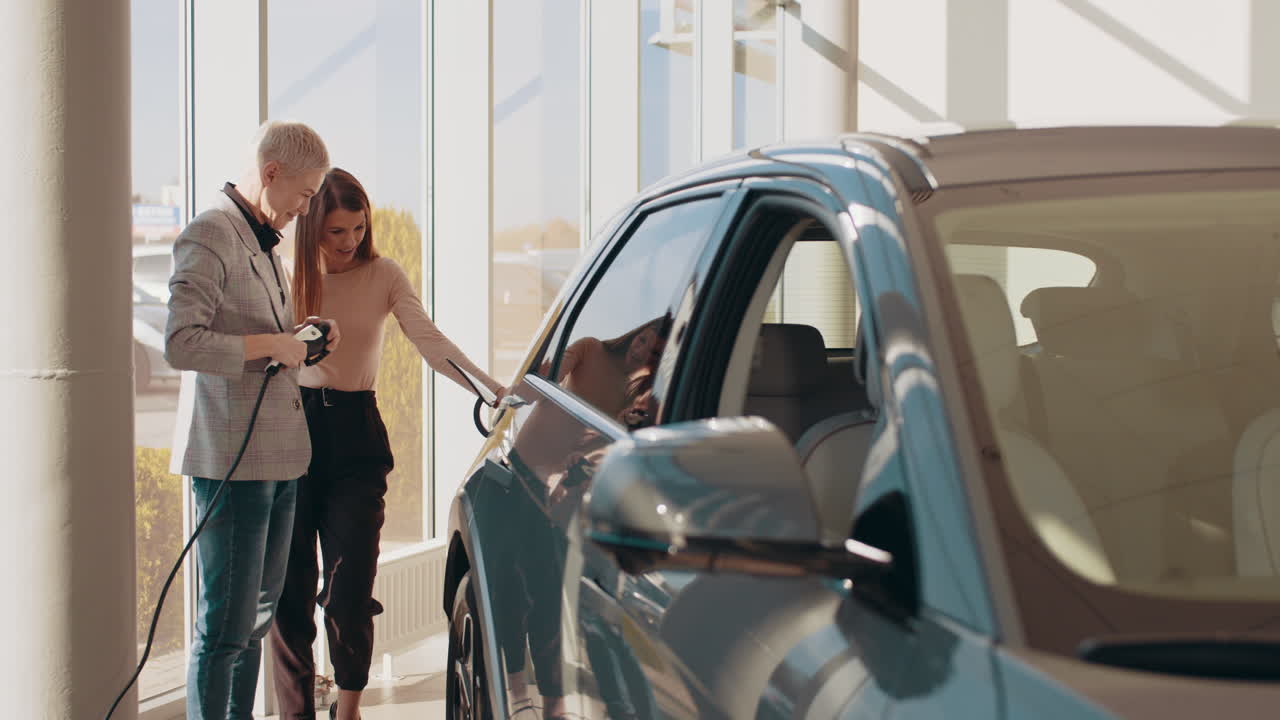 dos mujeres discutiendo un coche eléctrico en una sala de exposiciones