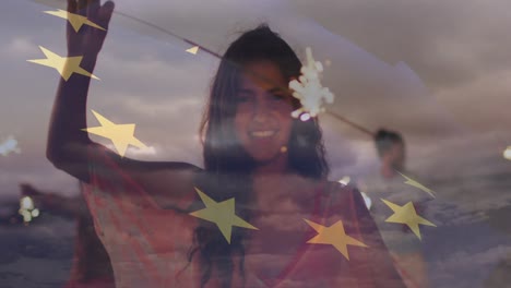 Animation-of-flag-of-european-union-over-happy-biracial-woman-with-sparklers-on-beach