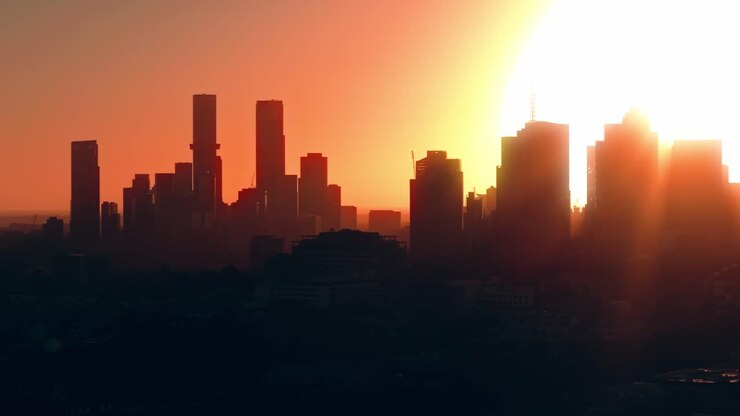Horizonte do CBD de Melbourne brilhando ao pôr do sol visto de Abbotsford em tomada aérea de drone, com fundo de silhueta em órbita.