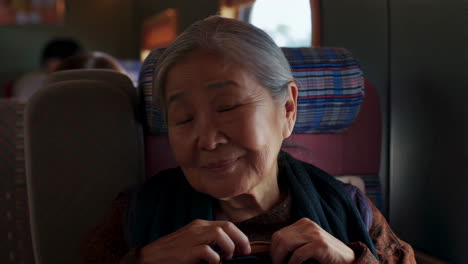 elderly asian woman smiling and content on a train