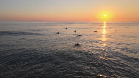 surfers waiting for a wave at sunset