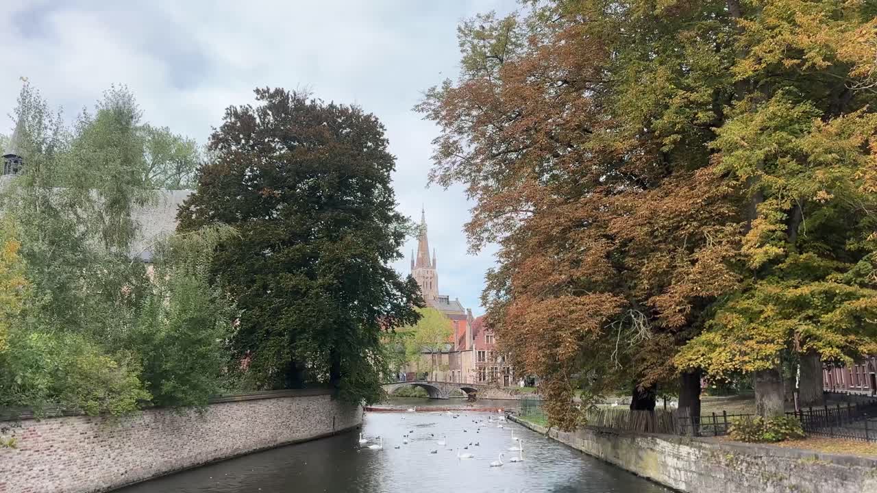 Peaceful view of colorful autumn foliage reflecting in the calm canal water in Bruges, Belgium