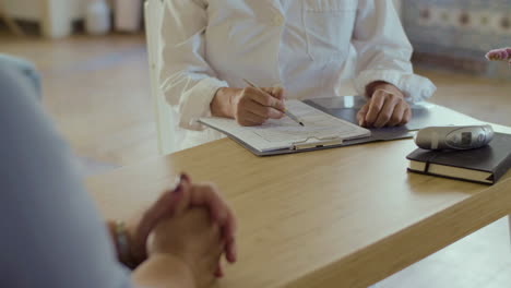 Close-up-shot-of-doctor-writing-notes-of-patients-health-at-home