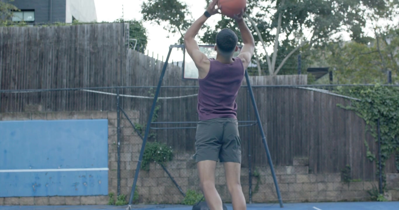 African American man practicing in purple top dribbling shooting on blue court chasing basketball