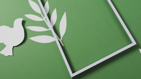 close up of white dove with frame and leaf and copy space on green background