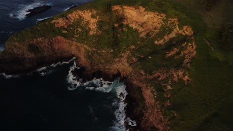 aerial parallax shot of the beautiful coastline of norfolk island, australia with views of the majestic cliffs with vegetation and the deep blue sea while waves bounce off the shore