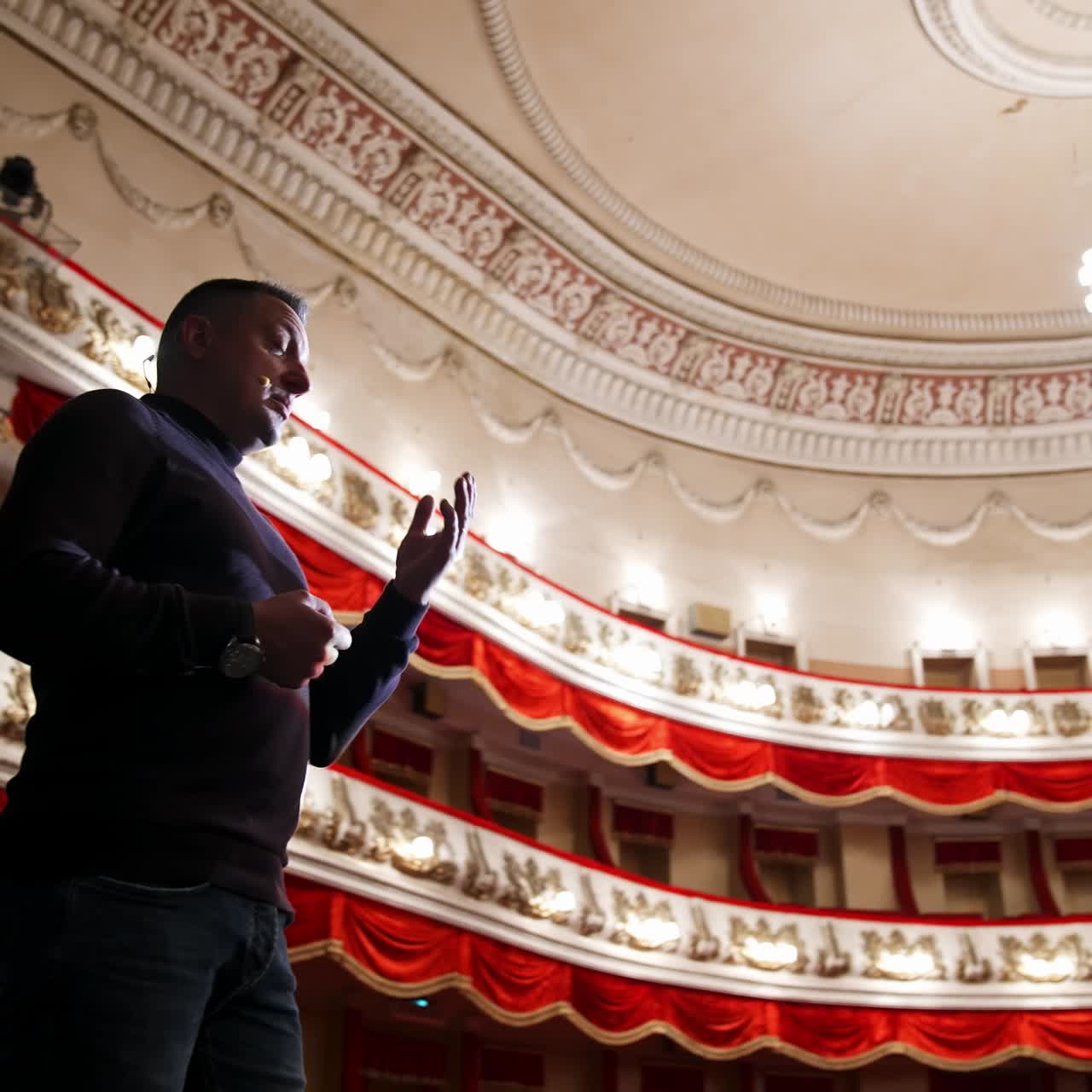 Actor man on a stage. Man wearing sweater performing on a scene in theatre. View from below