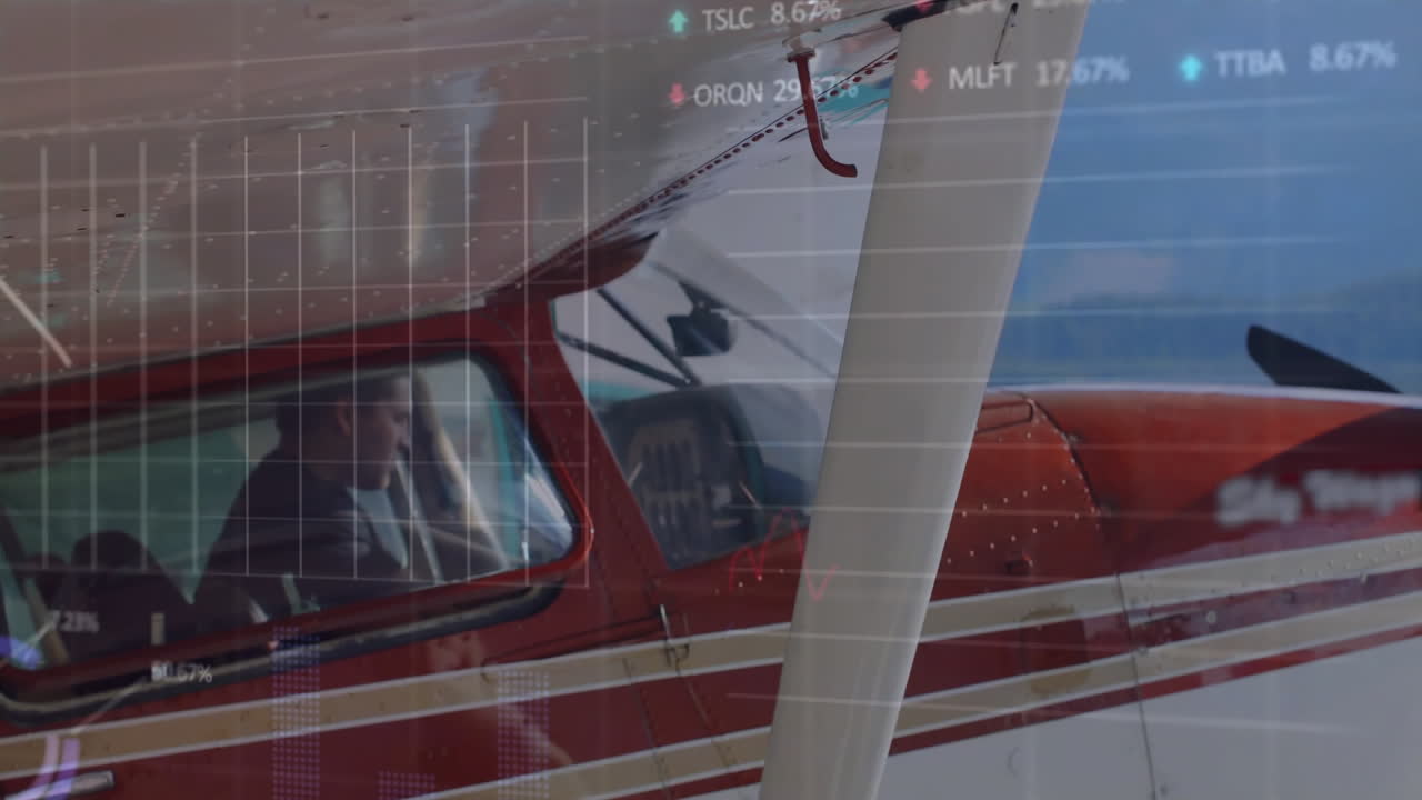 pilot sitting in cockpit of red white airplane, showing stock market grid and charts