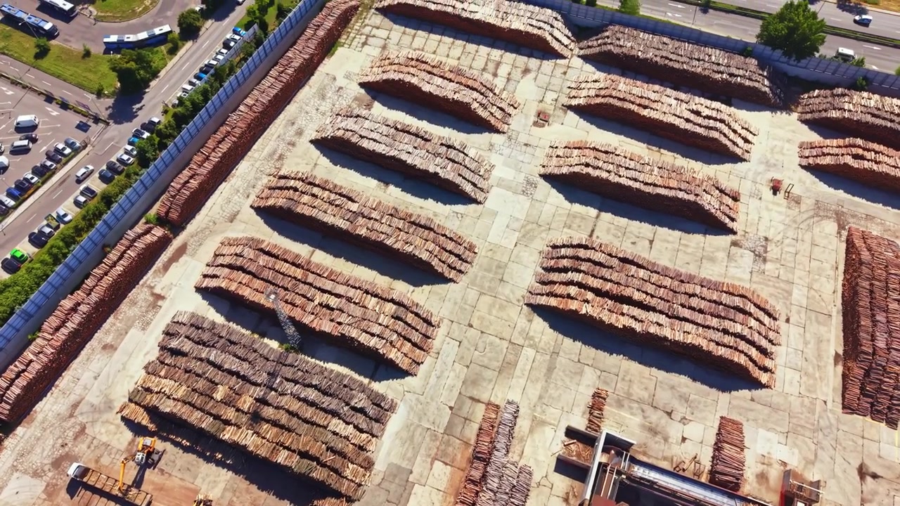 Area di lavorazione del legno con pile di materie prime e spazio di lavoro in un grande sito industriale di giorno.