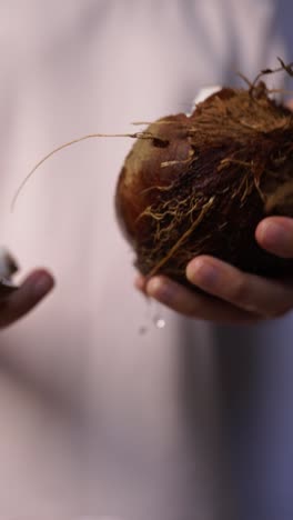 person draining water from a coconut