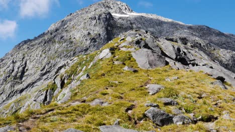 tiro inclinado hacia arriba de una maravillosa montaña rocosa y verde contra el cielo azul en verano - caminata de sillín gertrude en nueva zelanda