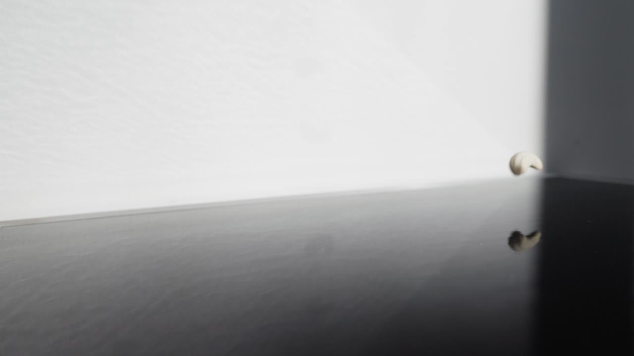 반사 표면에 떨어지는 캐슈넛의 정적 슬로우 모션 샷