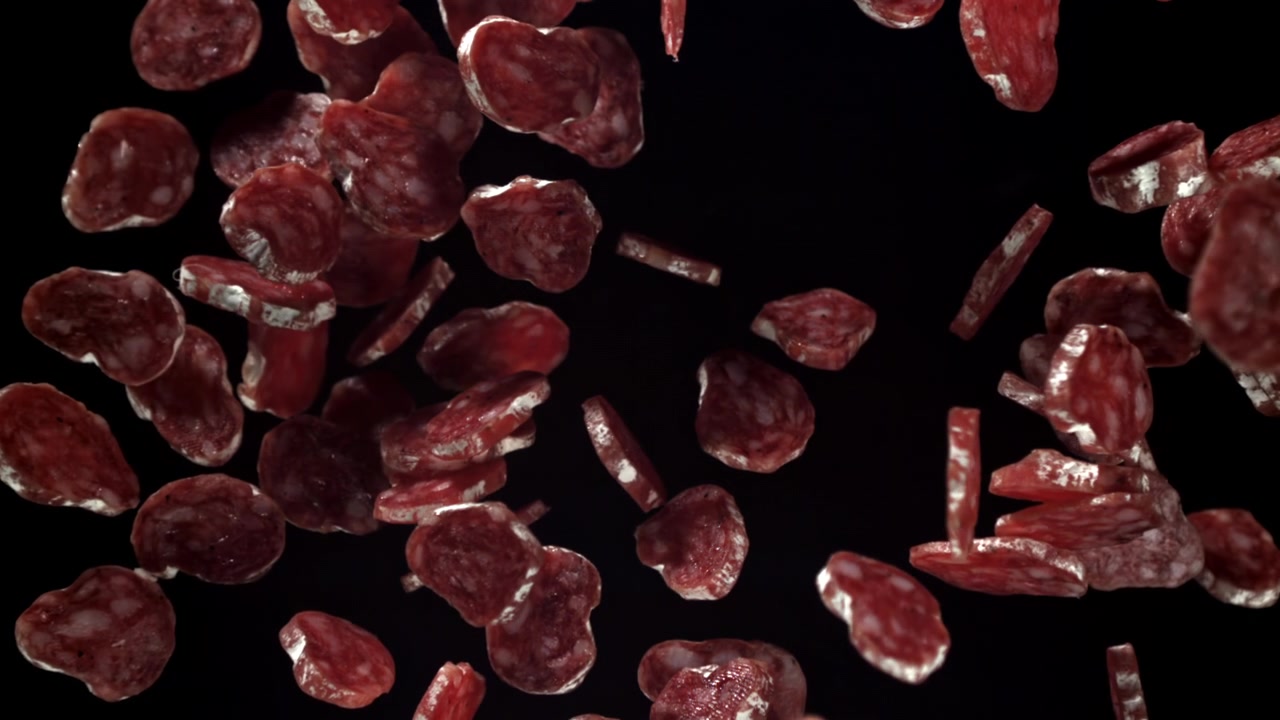 Slices of Salami Falling and Floating in Slow Motion on Black Background