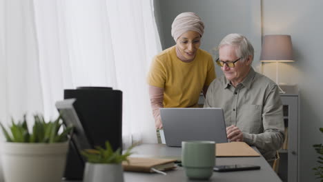 mujer árabe enseñando a un anciano a usar una laptop