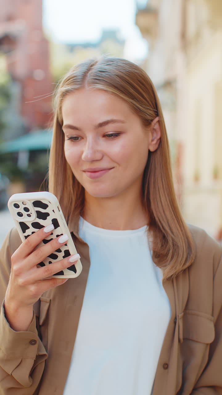 Beautiful young woman using smartphone typing text messages thinking and browsing internet on street