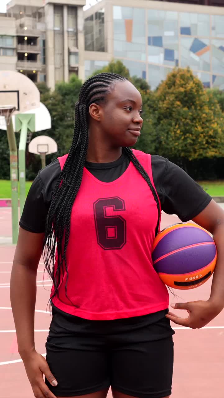 Ung kvinde med basketball på udendørs bane